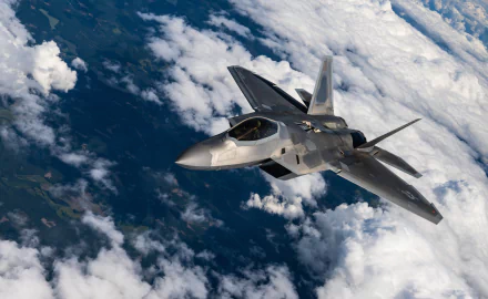 Lockheed Martin F-22 Raptor military jet soaring above clouds, captured in a stunning 4K Ultra HD PC desktop wallpaper and background.
