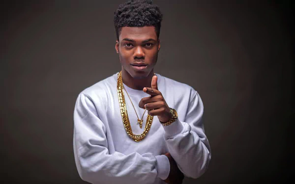 Stylish HD desktop wallpaper featuring a person pointing at the camera, wearing a white shirt and gold chains, with a grey background for a sophisticated look.