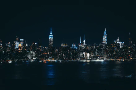 2K Quad HD PC desktop wallpaper and background: panoramic man-made city skyline at night, illuminated skyscrapers reflecting across calm water.