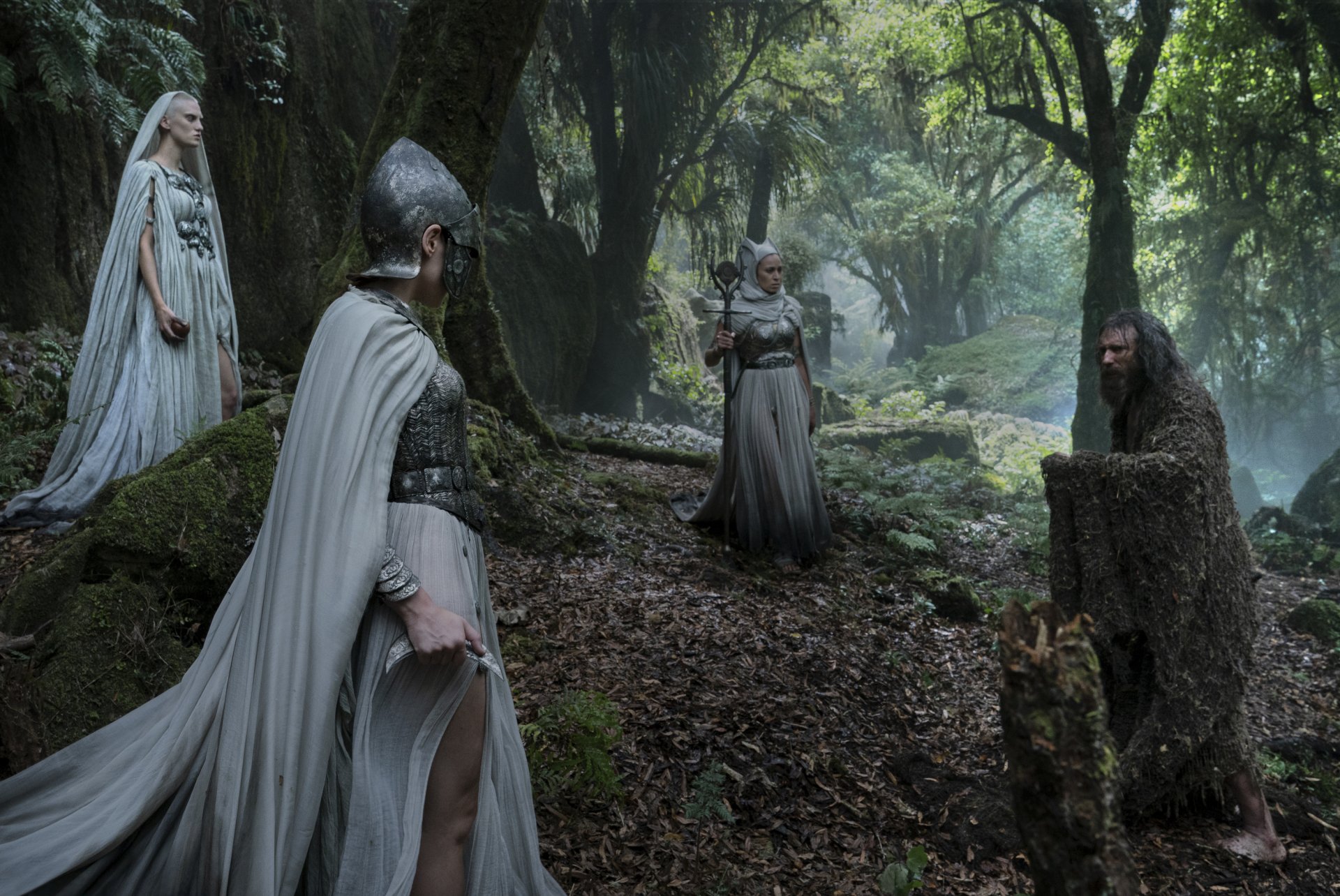 HD desktop wallpaper from The Lord of the Rings: The Rings of Power TV show, showing four characters in medieval attire in a misty, forested setting.
