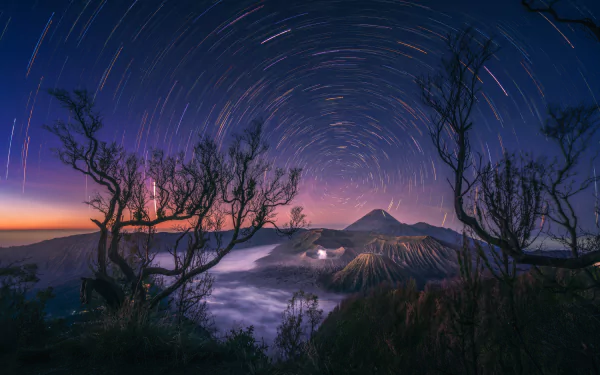 Stunning star trails above Mount Bromo in Indonesia at night, creating a mesmerizing natural display on a high-definition desktop wallpaper.