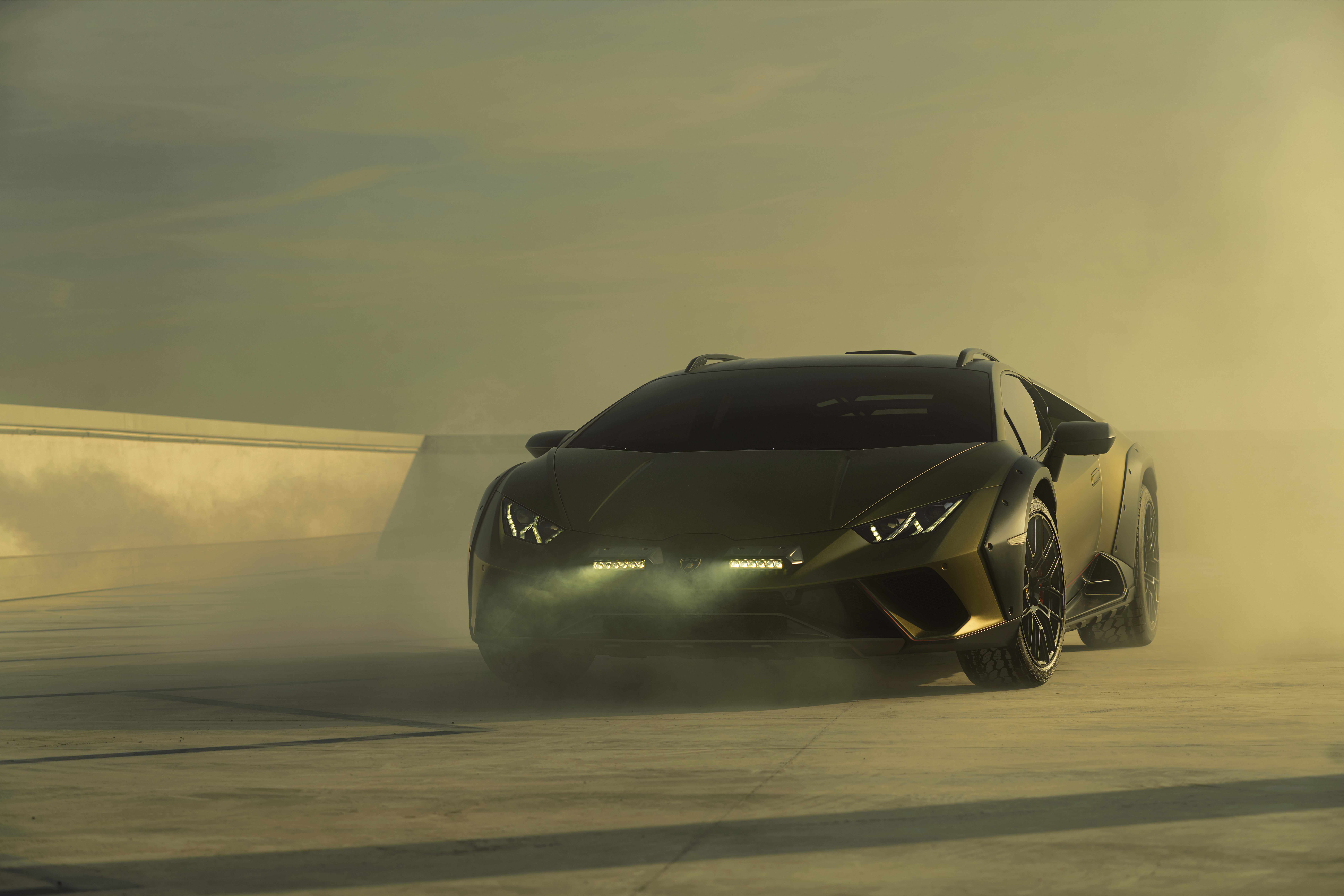 Lamborghini Huracán Sterrato roaring through sandy terrain in high-definition desktop wallpaper.
