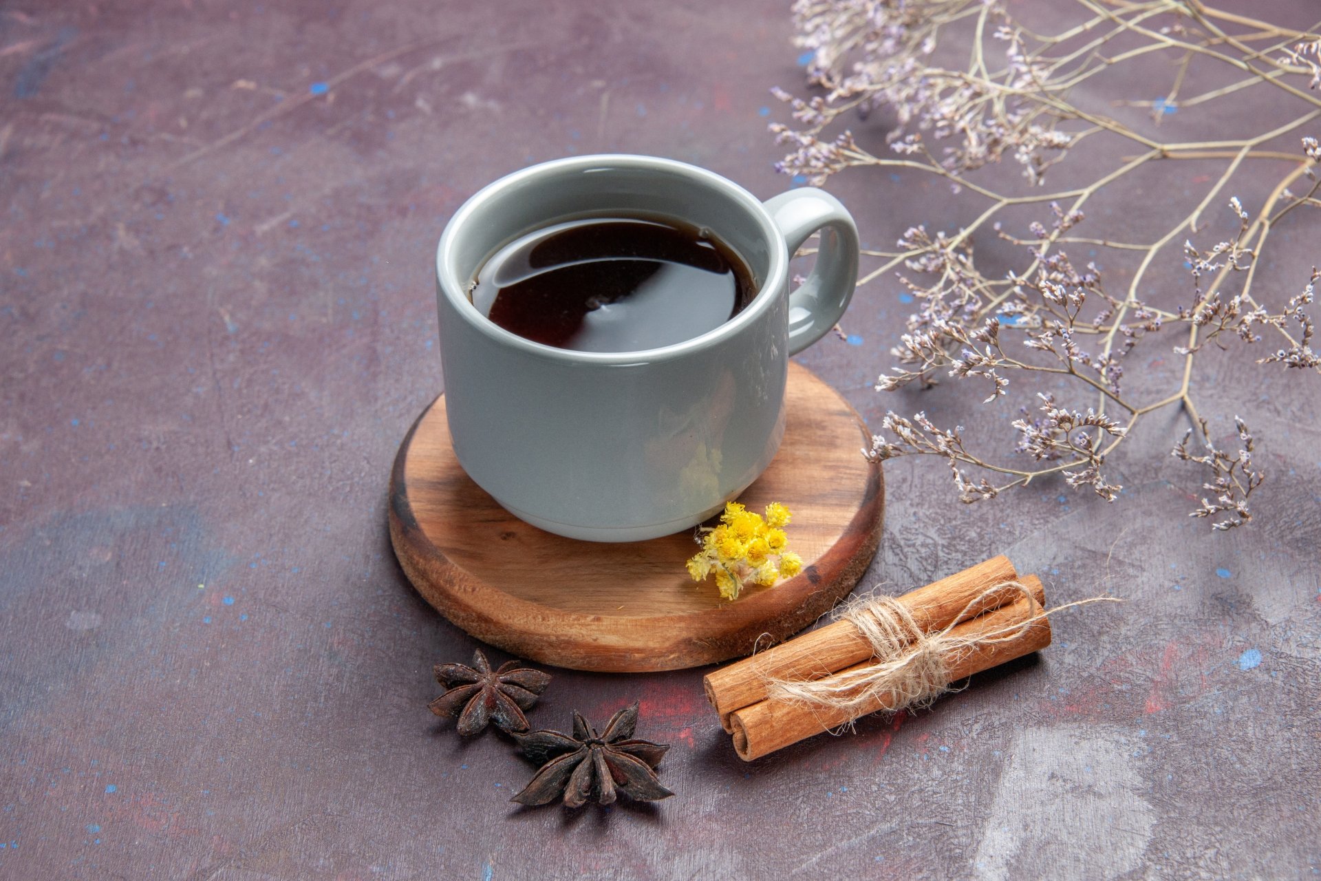 A 4K Ultra HD PC desktop wallpaper featuring a cup of black coffee on a wooden coaster, accompanied by cinnamon sticks, star anise, and dried flowers on a textured surface.