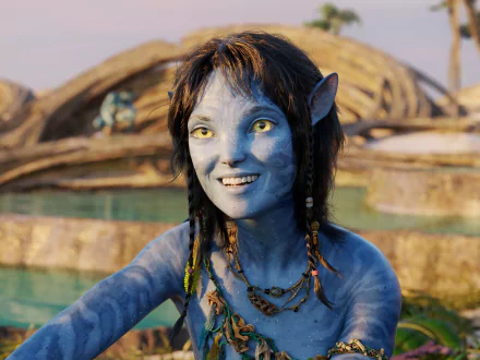HD PC desktop wallpaper featuring a character from the movie Avatar: The Way of Water, showcasing a blue-skinned, yellow-eyed Na'vi with braided hair and a joyful expression.