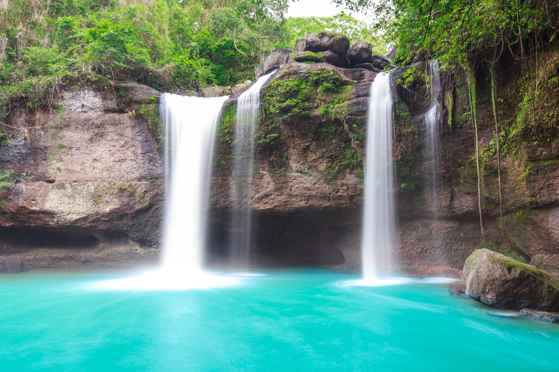 4K Ultra HD desktop wallpaper showcasing a serene nature scene with twin waterfalls cascading into a clear turquoise pool surrounded by lush green foliage.