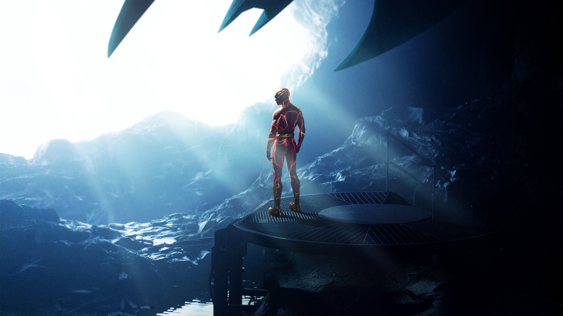 4K Ultra HD PC desktop wallpaper: The Flash (2023) in a scarlet suit stands on a rocky platform inside a glowing cavern, a giant bat-shaped silhouette looming overhead.