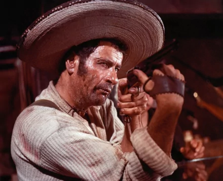 Eli Wallach in a striking scene from The Good, the Bad and the Ugly, showcasing his intense character with a gun, against a dramatic western backdrop in this HD wallpaper.