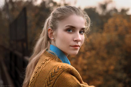 HD PC desktop wallpaper: portrait of a woman model with a blonde ponytail in a mustard knit sweater and blue collar, set against a soft autumnal outdoor background.