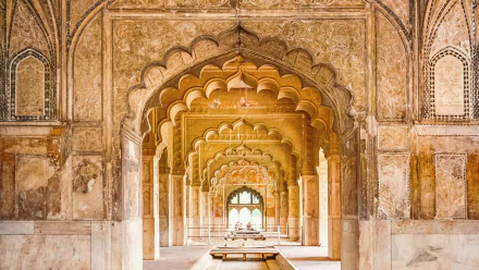 Symmetrical arched corridor inside the Red Fort, warm sandstone details and repeating vaults — HD PC desktop wallpaper of man-made Mughal architecture.