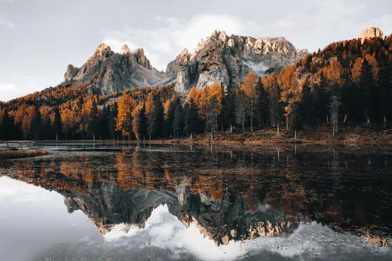 4K Ultra HD desktop wallpaper showing a tranquil lake reflecting rugged mountains and autumn-colored trees under a cloudy sky.