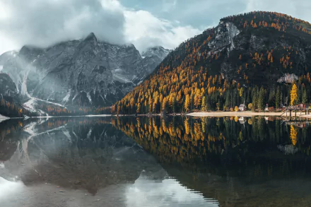 4K Ultra HD wallpaper featuring a serene mountain lake with autumn trees reflecting perfectly in the calm water under a cloudy sky.