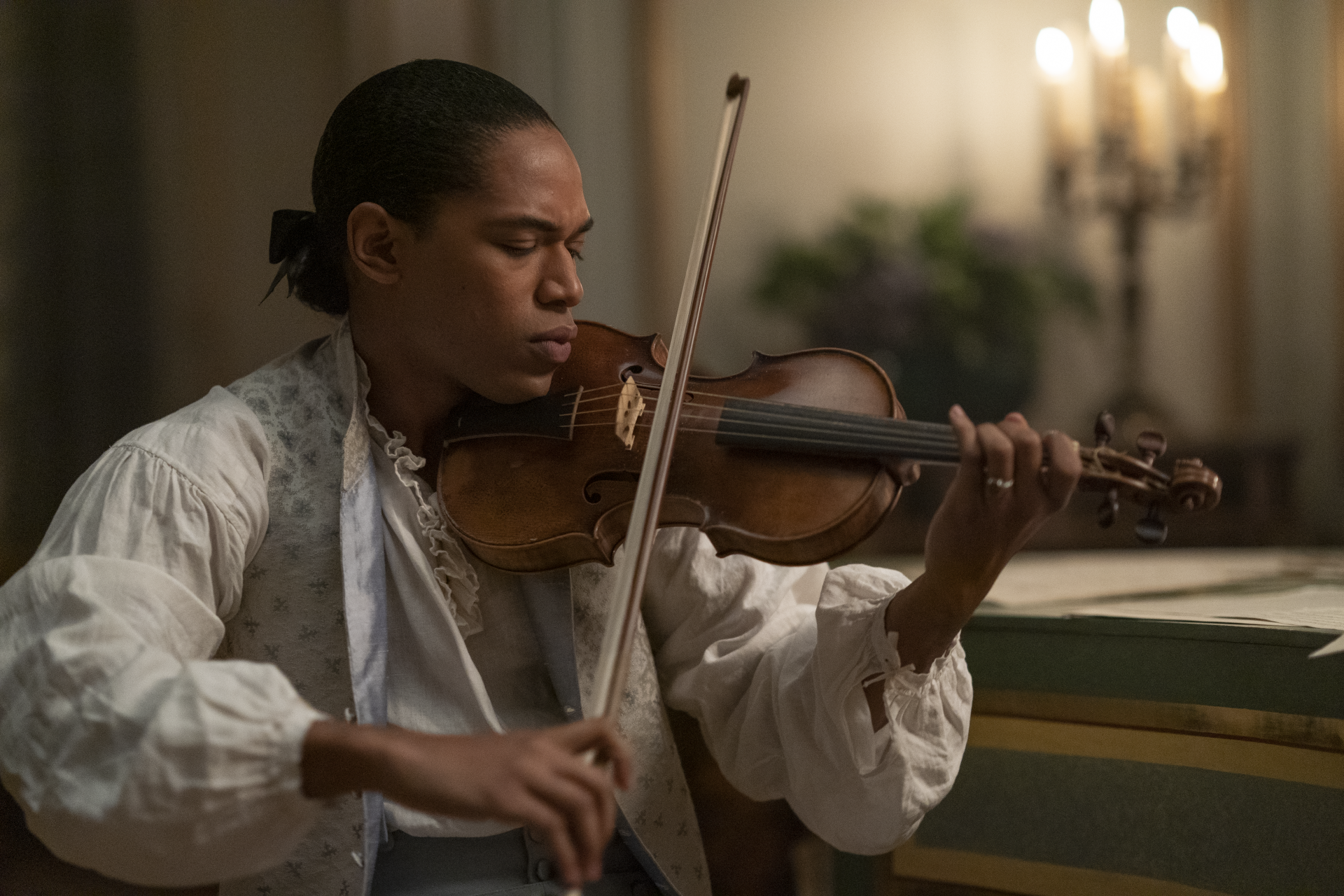 A person in historical clothing playing the violin with intense focus, suitable as a Chevalier-themed HD desktop wallpaper and background.