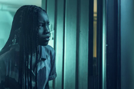A young woman with braided hair stares intently out a window, captured in a moody, atmospheric scene from the movie Insidious: The Red Door. This image serves as an HD desktop wallpaper.