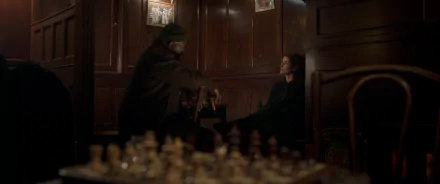 A scene from the TV show Secret Invasion, featuring two characters in a dimly lit space, with a chessboard in the foreground, creating an atmosphere of intrigue and tension.