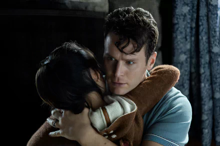 A scene from the movie Knock at the Cabin, featuring a man embracing a child, conveying a sense of tension and emotion against a dark, atmospheric background. HD desktop wallpaper.