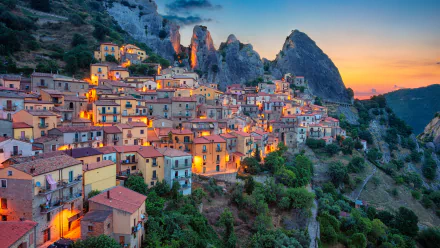 A vibrant 4K Ultra HD wallpaper of Castelmezzano, a charming man-made town nestled among rocky peaks at sunset.