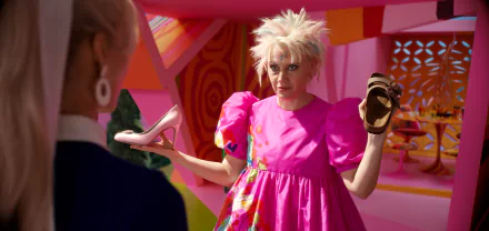 Kate McKinnon in a vibrant pink dress holds up two shoes, contrasting styles, set against a colorful background from the movie Barbie (2023). Bright and playful HD wallpaper.