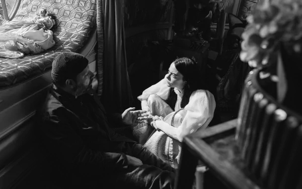 Black and white HD desktop wallpaper from 'Poor Things' featuring a man and a woman in a vintage setting, with emotional facial expressions.