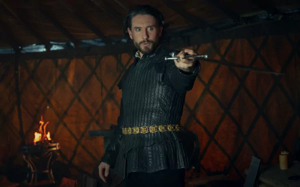 A character from The Witcher stands confidently in a rustic setting, holding a sword. The warm glow of a fire illuminates the background, creating a captivating HD wallpaper.