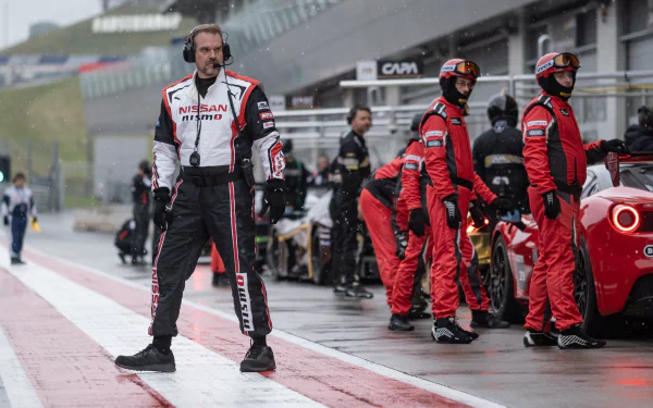 HD wallpaper featuring a scene from Gran Turismo: The Movie with a racing team in pit lane preparing for action, promoting the thrilling motorsport atmosphere.