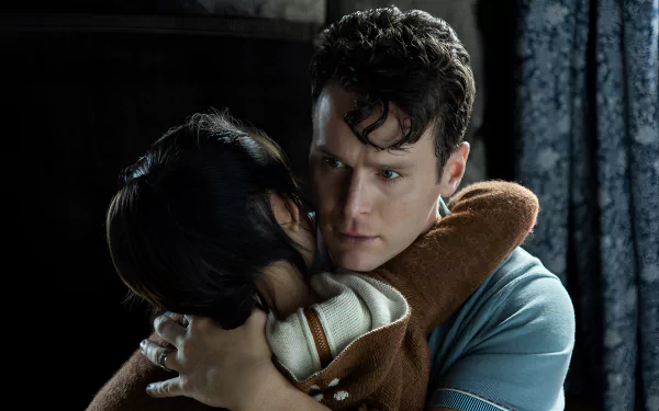 A scene from the movie Knock at the Cabin, featuring a man embracing a child, conveying a sense of tension and emotion against a dark, atmospheric background. HD desktop wallpaper.