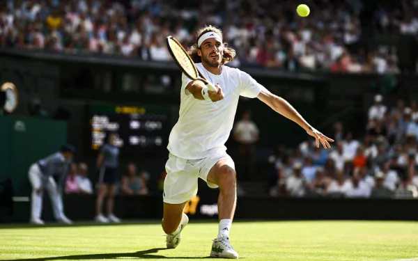 Stefanos Tsitsipas in action at Wimbledon 2023, reaching for a tennis ball on a sunlit court, captured in a dynamic HD desktop wallpaper.