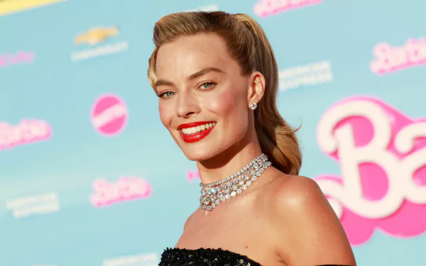 Margot Robbie dazzles at the Barbie (2023) event, showcasing a glamorous look with a sparkling necklace and a bold red lip against a vibrant backdrop.