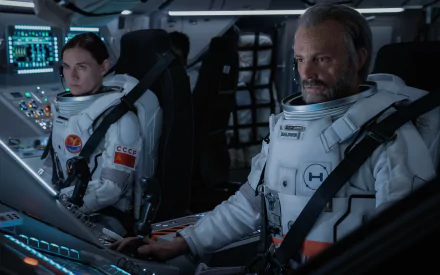 HD desktop wallpaper from For All Mankind featuring two astronauts in a spacecraft control room.