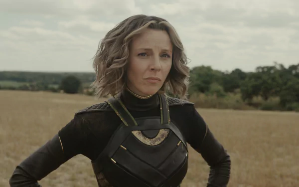 A character from the TV show Loki stands confidently in a sunlit field, showcasing a unique costume against a backdrop of greenery and clouds. A striking HD wallpaper.