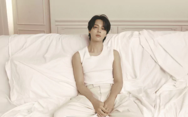 HD desktop wallpaper featuring BTS member Jimin in a serene setting, dressed in white, sitting on a couch with a thoughtful expression.