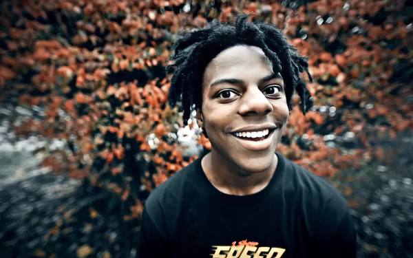 A high-definition background featuring IShowSpeed, smiling widely against a backdrop of vibrant orange foliage, creating an energetic and engaging atmosphere.