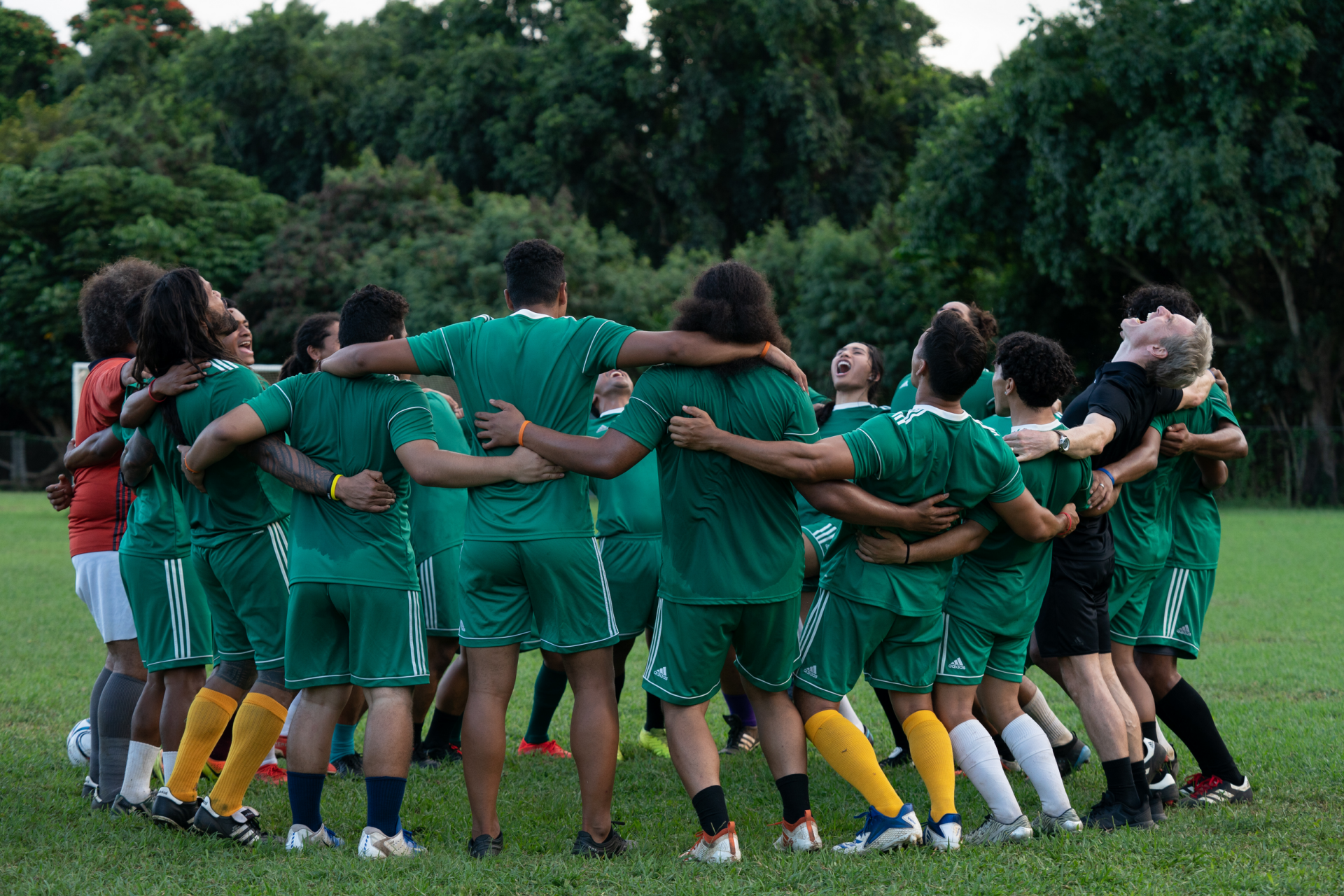 HD wallpaper of Next Goal Wins 2023 movie showing team huddle on soccer field, depicting teamwork and sportsmanship.