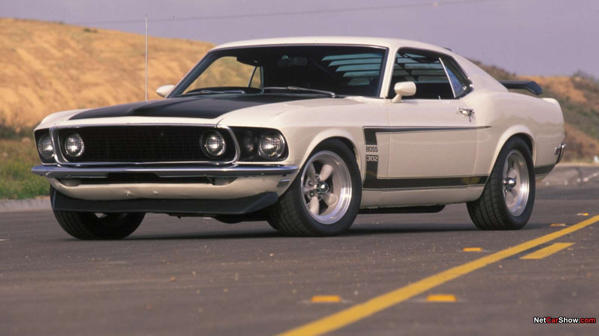 HD desktop wallpaper featuring a classic white Ford Mustang Boss 302 muscle car parked on a desert road.