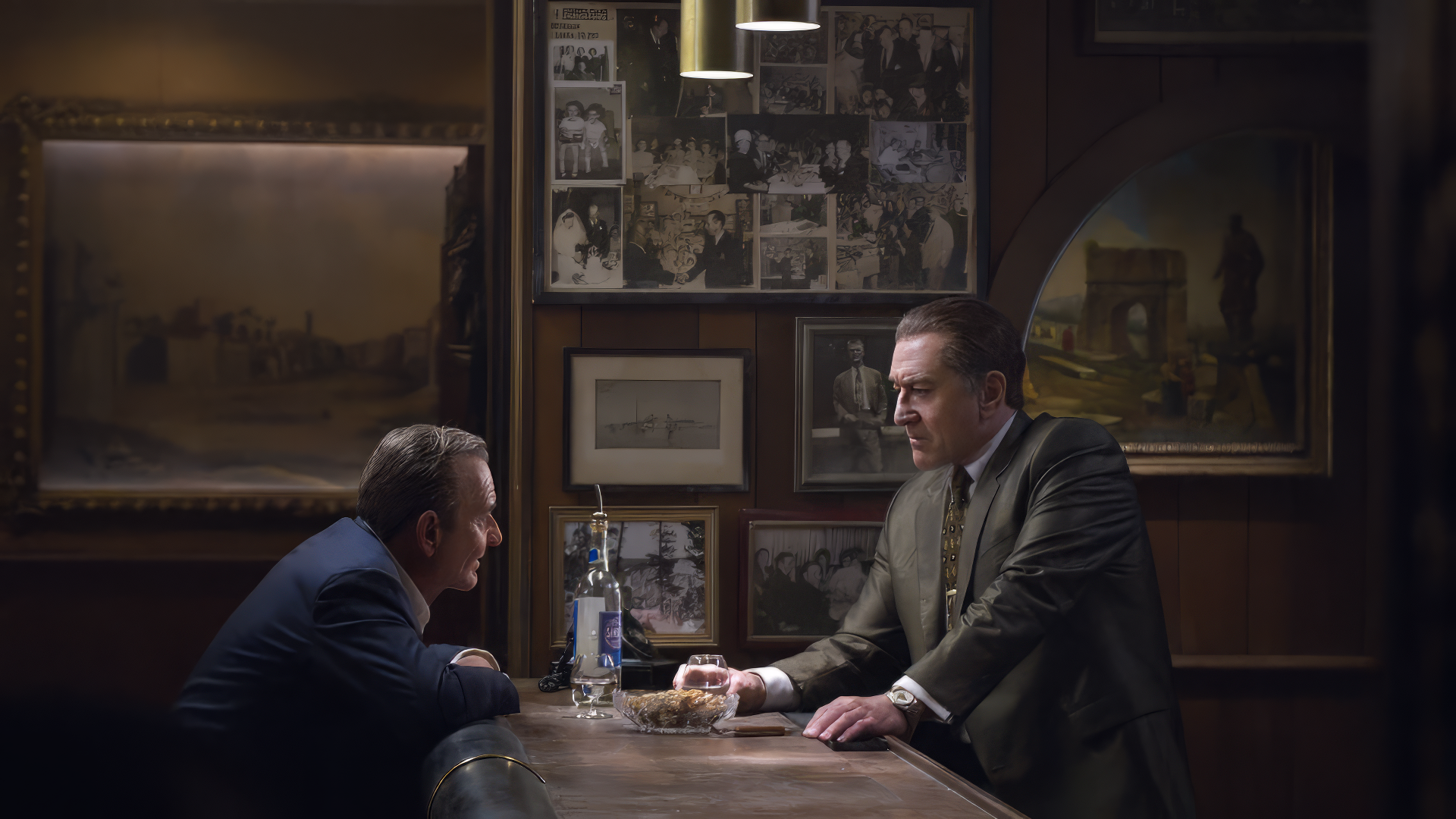 HD desktop wallpaper featuring a scene from Killers of the Flower Moon with two characters in a dimly lit room with vintage decor.