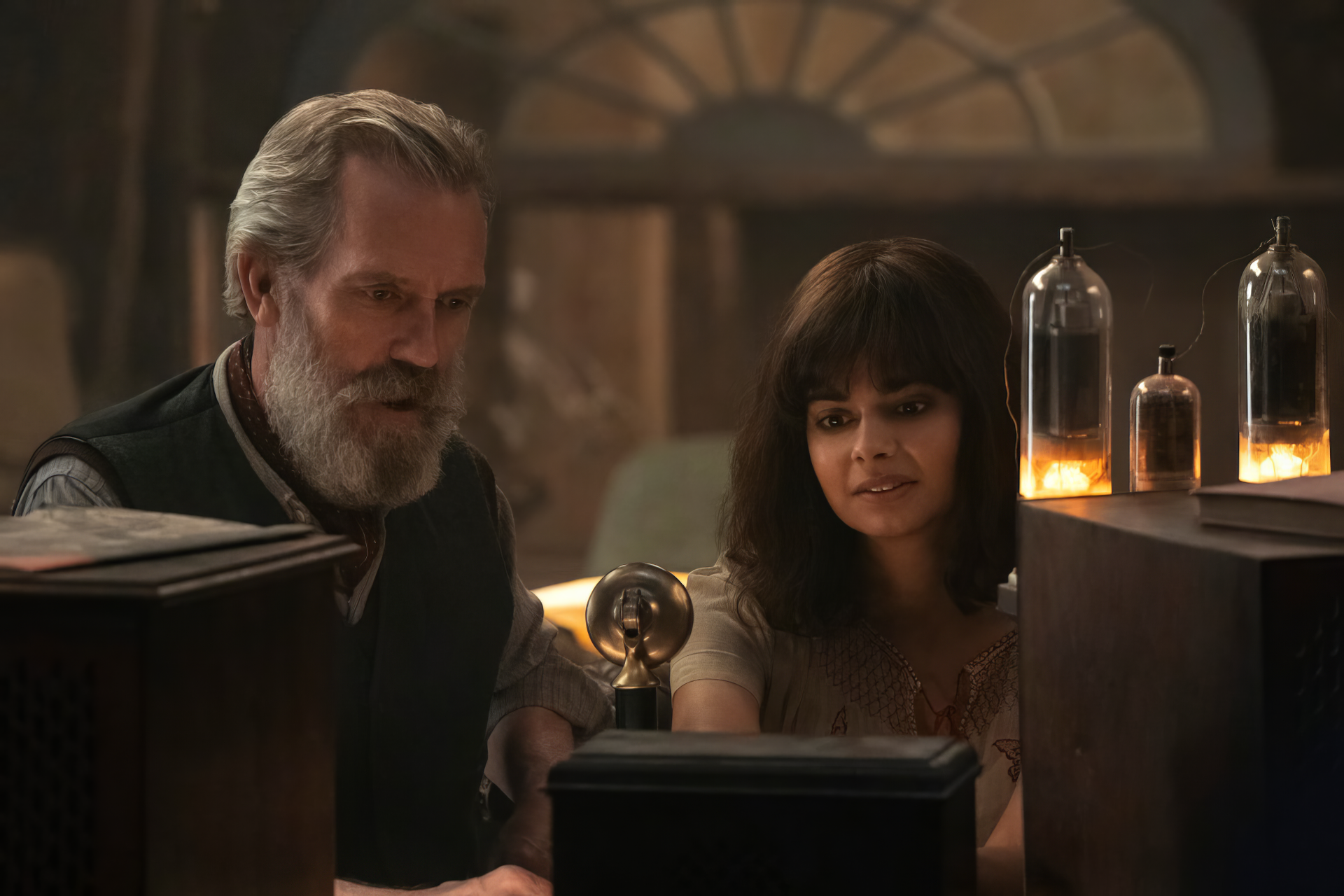 HD wallpaper featuring a scene from the TV show 'All the Light We Cannot See' with two characters engaging with a radio apparatus, creating a warm and intriguing ambiance.