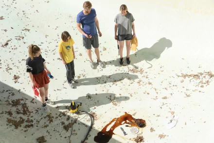 A scene from the movie *Night Swim*, featuring four young people examining a pool with debris scattered around, set against a bright, sunlit background. HD wallpaper quality.