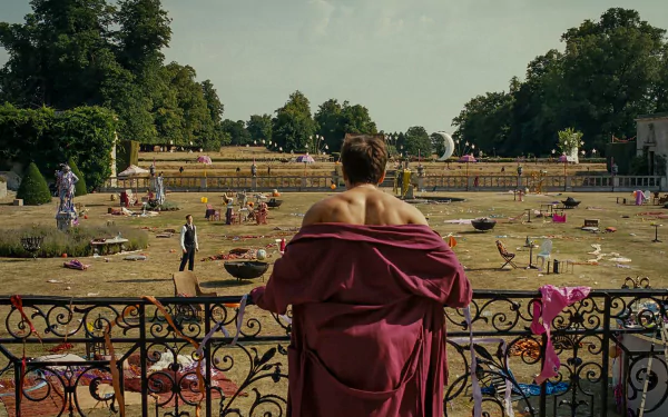 HD desktop wallpaper from Saltburn (2023) featuring a person draped in a red cloth looking over a busy park scene.