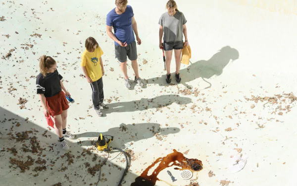 A scene from the movie *Night Swim*, featuring four young people examining a pool with debris scattered around, set against a bright, sunlit background. HD wallpaper quality.