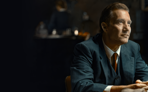 HD wallpaper of a man in a blue suit portraying a character in a dimly lit setting, suggestive of a scene from the TV show Monsieur Spade.