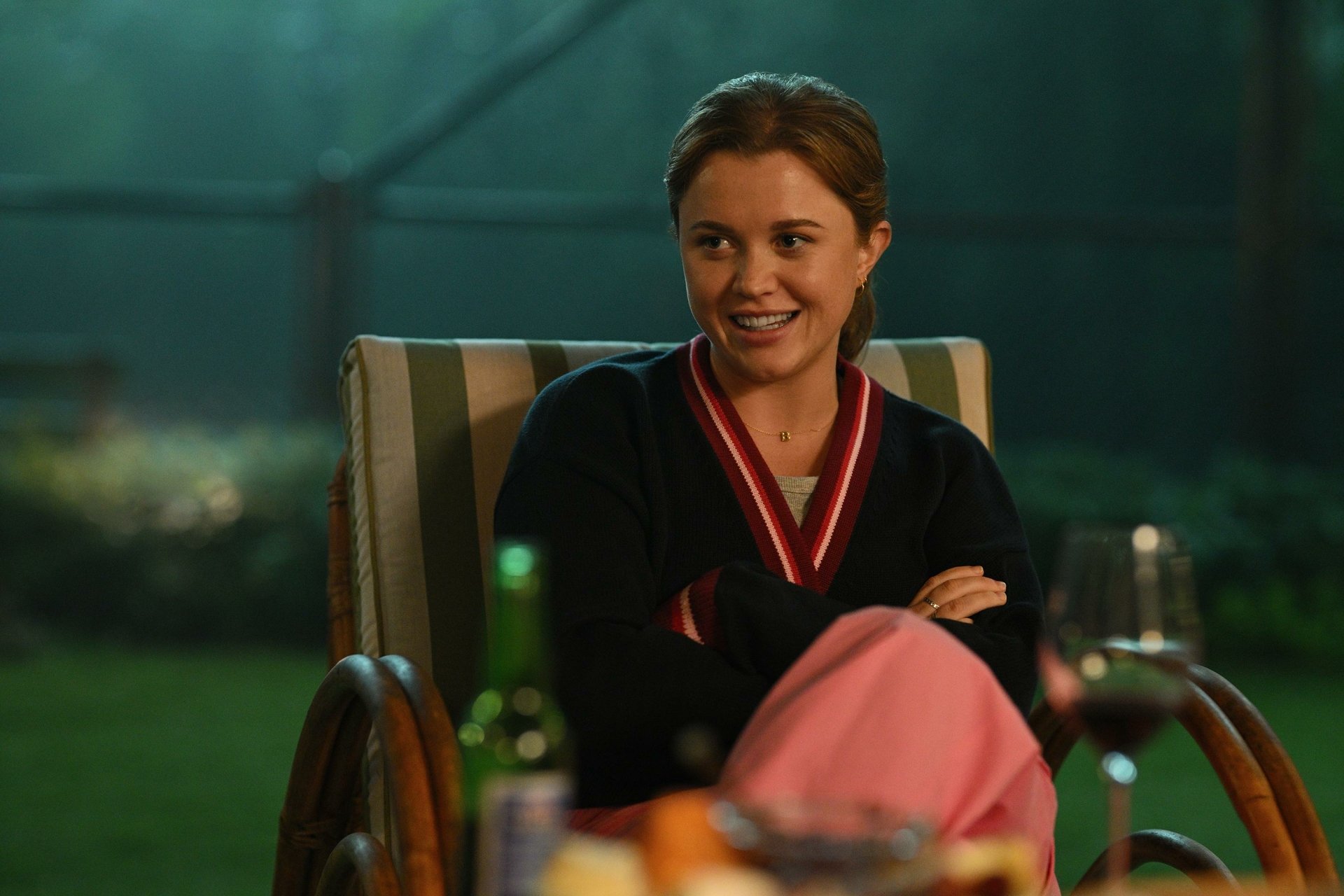 HD desktop wallpaper featuring a scene from the TV show Apples Never Fall with a smiling character sitting in a garden chair at nighttime.