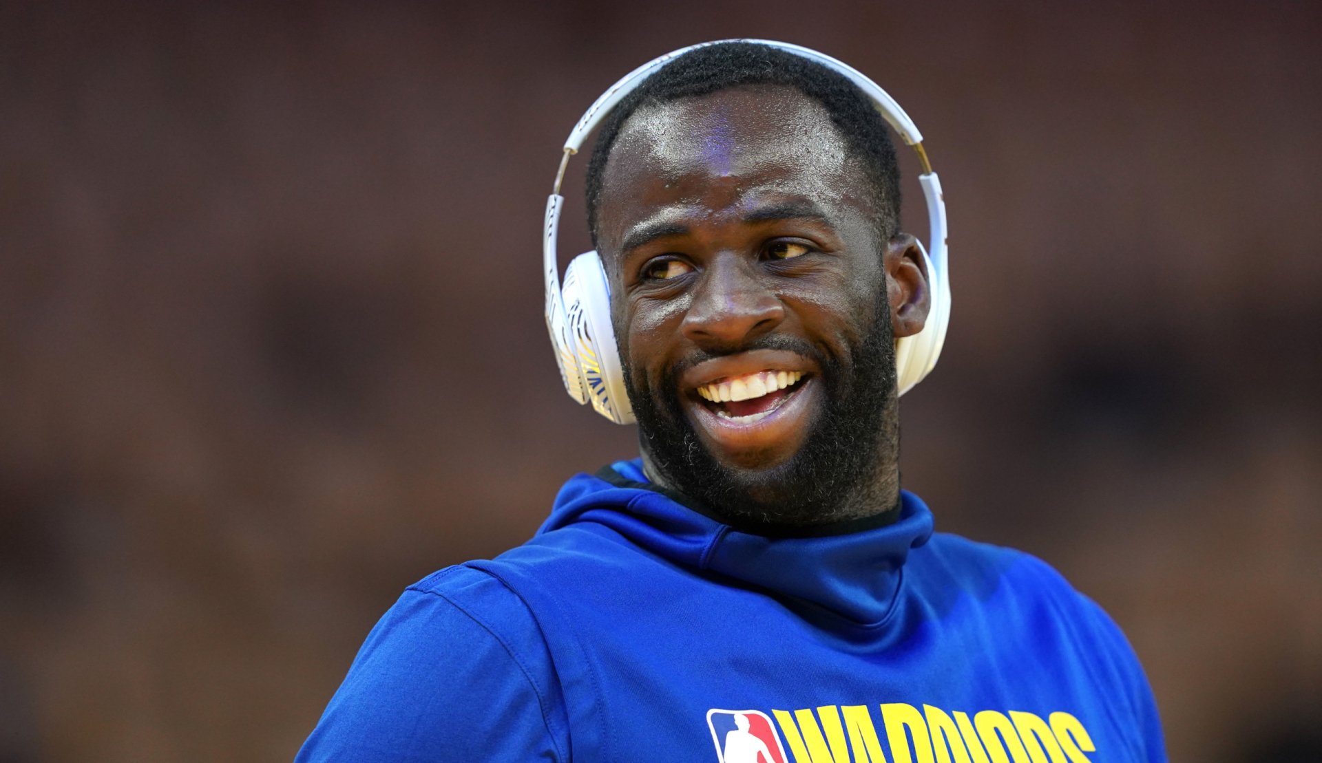 Draymond Green of the Golden State Warriors smiles while wearing headphones during warm-ups. This HD image captures the energy and spirit of NBA basketball.