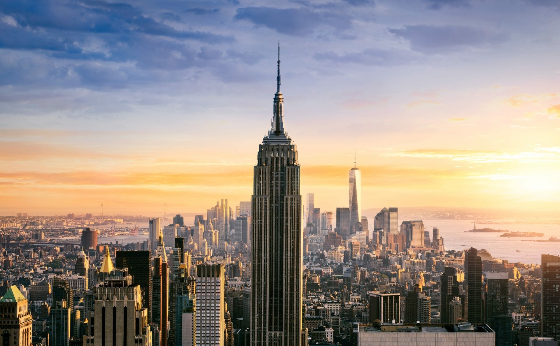 A stunning panoramic view of the Empire State Building at sunset, showcasing the iconic skyscraper amidst the vibrant New York City skyline. An HD desktop wallpaper capturing urban elegance.