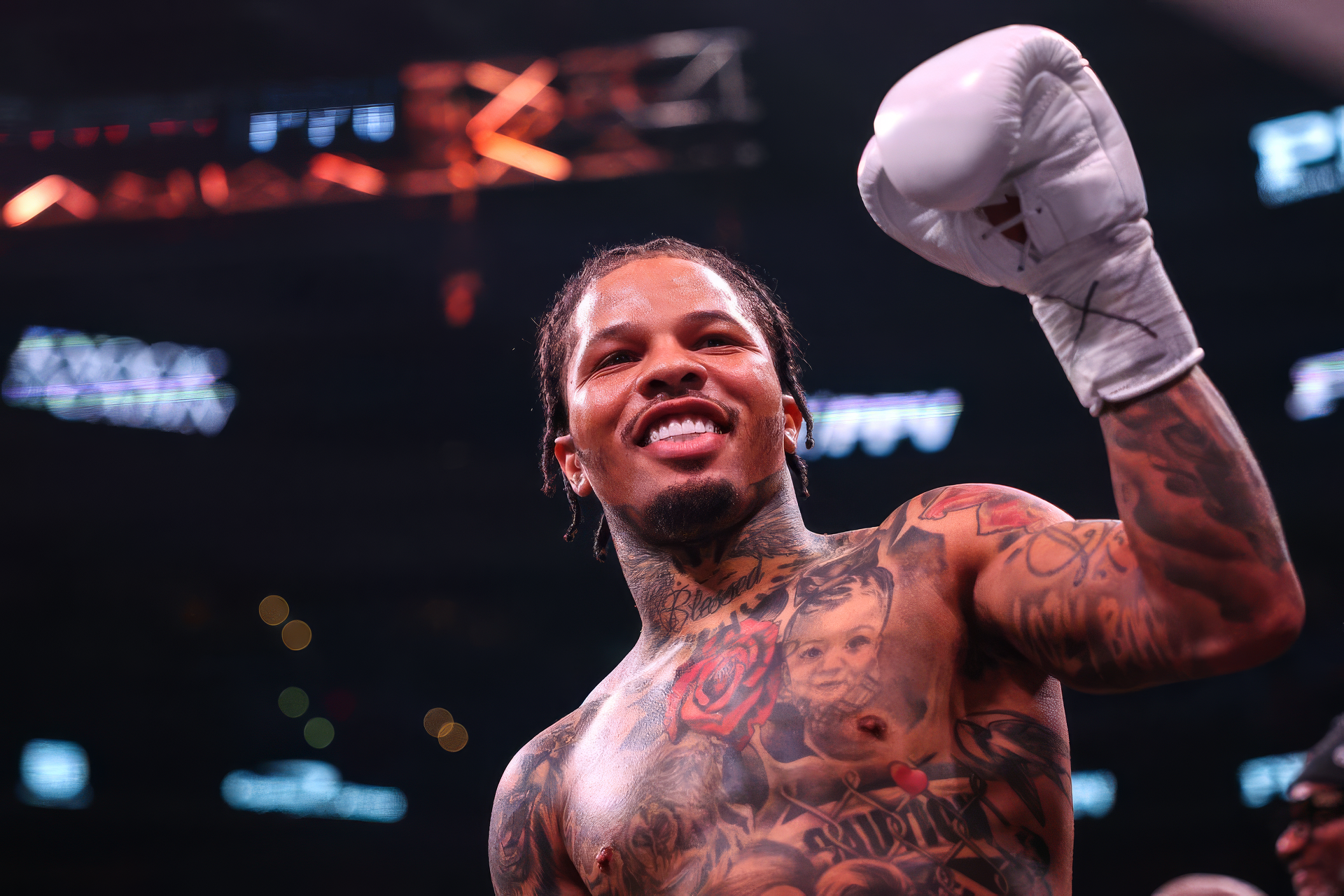 A boxer with tattoos triumphantly raises a gloved fist in the ring, exuding confidence and strength. The image serves as a HD desktop wallpaper and background.