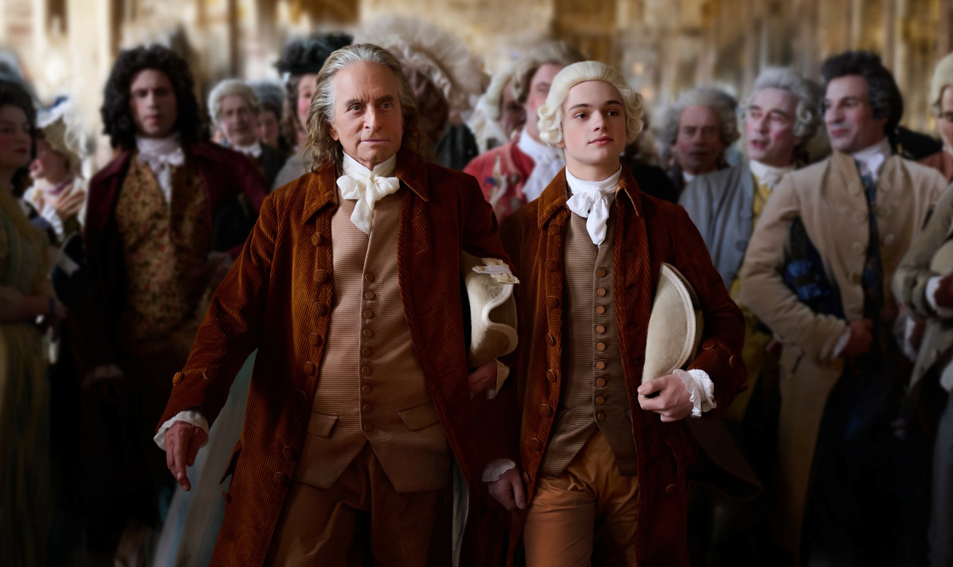 HD desktop wallpaper featuring two actors dressed in elegant 18th-century costumes, walking through a crowd of similarly dressed background characters, presumably from the TV show Franklin.