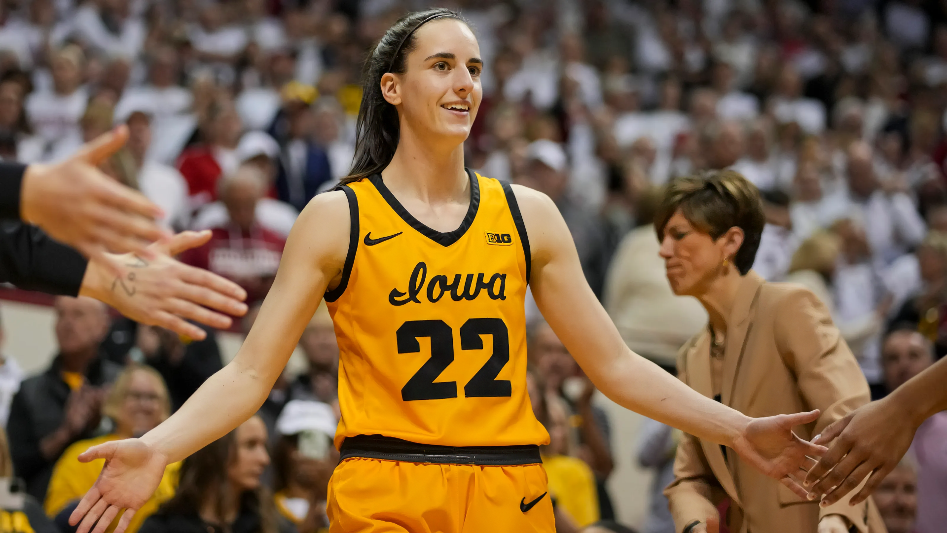 A smiling basketball player in an Iowa jersey with the number 22 receiving high-fives in a packed arena – HD desktop wallpaper and background.