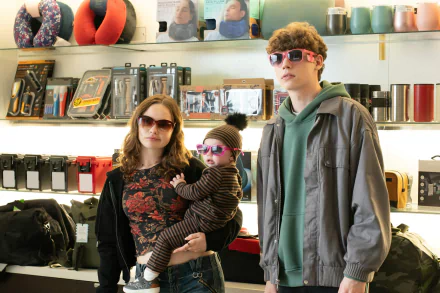 HD desktop wallpaper from the movie The Family Plan featuring two adults with sunglasses and a baby in a store.