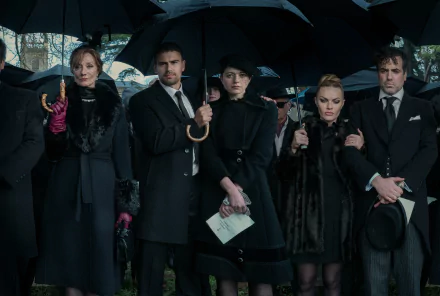 A dramatic scene from the TV show The Gentlemen (2024), featuring a group of solemn characters holding umbrellas and dressed in dark, formal attire at a gathering. HD desktop wallpaper.