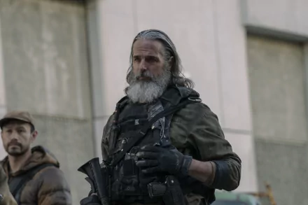 A striking HD wallpaper from The Last Of Us, featuring a rugged character with a beard, wearing tactical gear, set against a gritty urban backdrop.