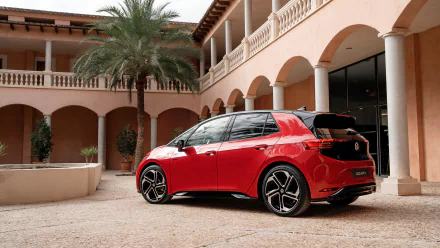 Red Volkswagen ID.3 GTX parked by a building, serving as a sleek HD desktop wallpaper of a modern electric vehicle.