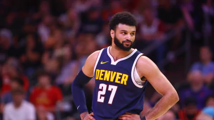 Jamal Murray of the Denver Nuggets stands focused during a game, showcasing his team's colors and determination in this HD desktop wallpaper.